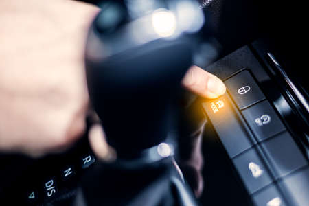 Selecting drive mode in the car. Manâ€™s hand touch the button on control panel