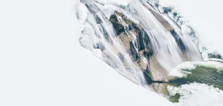 Flowing waterfall with snow and ice in winterの写真素材
