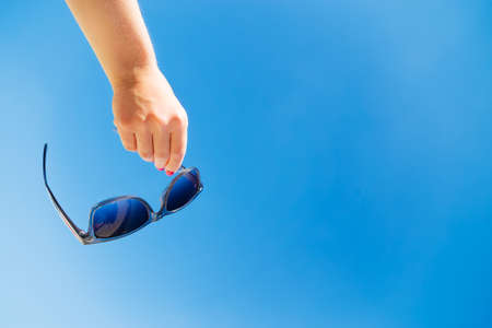 Hand hold sunglasses. Blue sky at sunny dayの写真素材