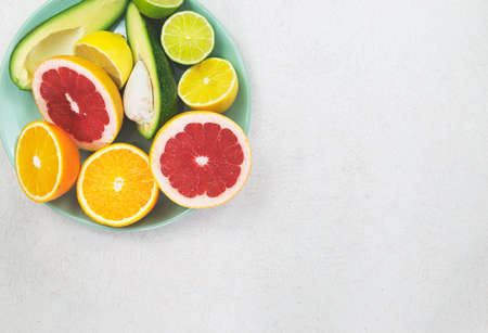 Cyan plate with sliced orange, grapefruit, lemon, lime and avocado on the old white tableの写真素材