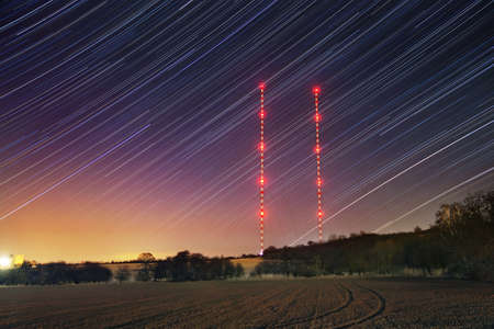 Star trails with transmitter towers in winter night. Starry sky with red lights.の写真素材