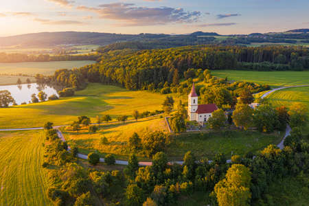 Church on the hill with sunlit summer landscape from above. Bysicky church near SPA town Lazne Belohrad, Czech Republic. Sunset gold light.の写真素材