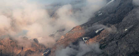 clouds moving along a mountain wall at sunsetの写真素材