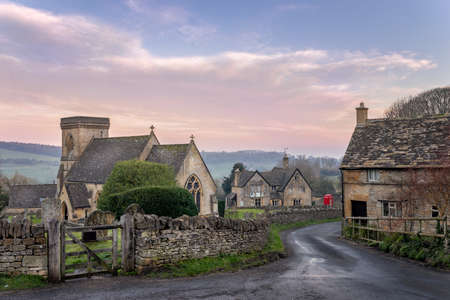 Snowshill church in the Cotswolds gloucestershire with lane leading past a cottage towards red...