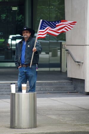 PORTLAND, OREGON JUNE 15 2016 Man in front of a federal courthouse waving a US flag protesting the court case against participants of the armed occupation of the Malheur National Wildlife Refuge.のeditorial素材