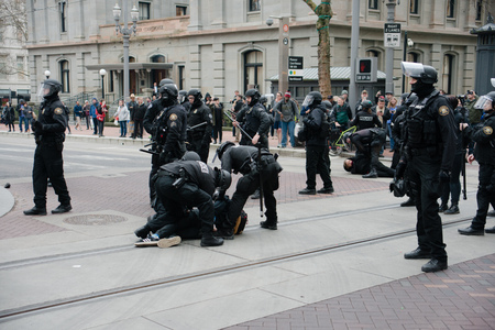 PORTLAND, OREGON JANUARY 25 2017, Police officers in riot gear, arresting people, clearing the roadway of protests of the police reaction to inauguration day protests who were blocking trafficのeditorial素材