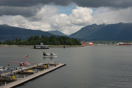 VANCOUVER CANADA JUNE 09 2017, A Seaplane taxis to prep to take off in the Burrard Inlet. Other seaplanes are docked in the foreground, a floating gas station is visible.のeditorial素材