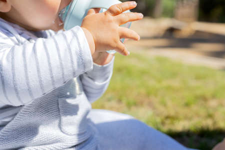 Baby boy holding his bottle with his handsの写真素材