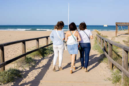Three women walking across a bridge on the beachの写真素材
