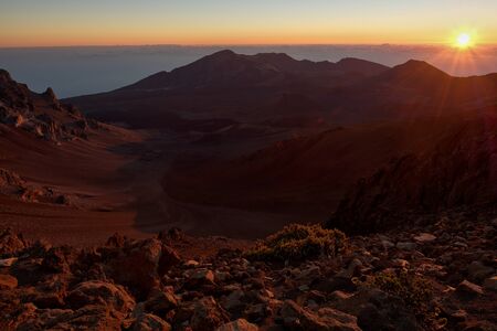 The sun's rays creeping over the horizon into the valleyの写真素材