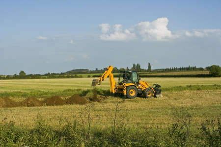 digger in countryside digging holes in the ground
