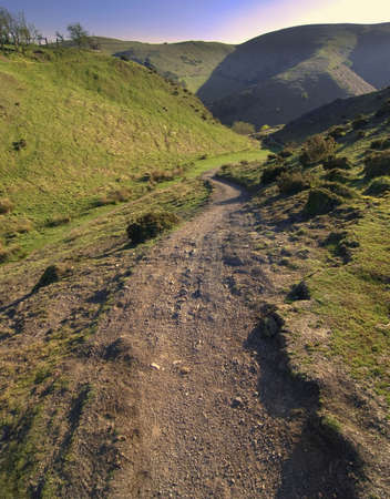 mountain peak sunlit footpath and moody clouds