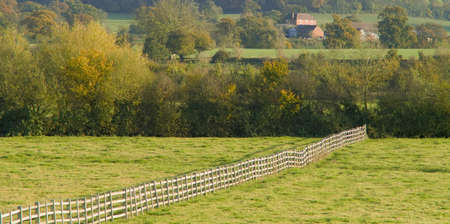 Farmland empty field with fence farmhouse in distance