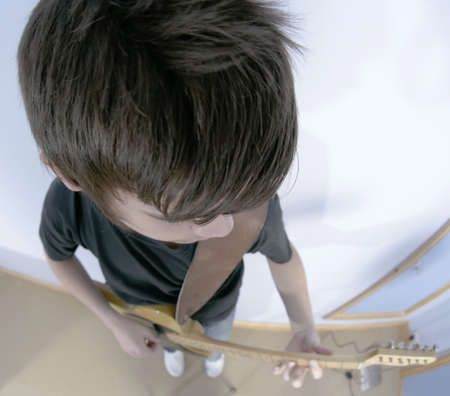 14 year old teenage boy playing punk rock on a vintage blonde fender telecaster type guitar in...