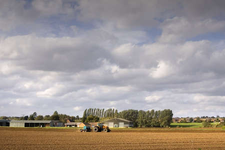 tractor ploughing a field of earthの写真素材