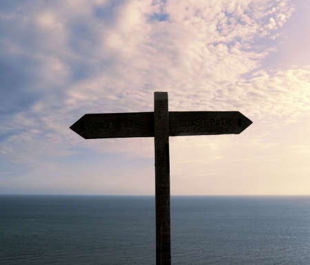 signpost with background of sunset sky and sea room for text to be addedの写真素材