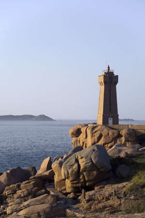 Sunset over rocks and lighthouse at Pars Kamor Ploumanach Breton Corniche Cote de Granit Rose Cotes d Armor Brittany France Europeの写真素材