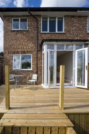 house with wooden decking and patio leading to gardenの写真素材