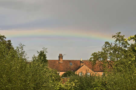 Suburban roof top crowned with a rainbowの写真素材