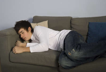 teenage boy sleeping on couchの写真素材