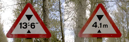  	Two road signs indicating the same bridge height in both imperial and metric measurementsの写真素材