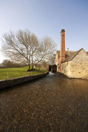 A view of lower slaughter village with the river eye and a mill wheelの写真素材