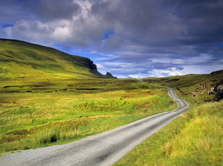 a desolate country road across moorland on the isle of syke with the quiraing in the distance - the isle of skye in Scotland, Great Britain UK a desolate country road across moorland on the isle of syke with the quiraing in the distance - the isle of skye in Scotland, Great Britain UK