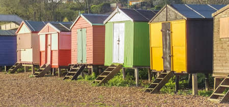 a row of beach huts on a sandy beach with sand dunes behind