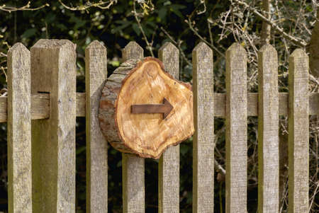 a wooden carved arrow on a fenceの写真素材