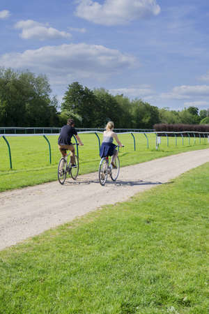couple cycling on cycle track around warwick racecourse park, midlands, uk の写真素材
