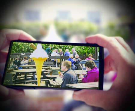 Senior woman in straw hat taking picture of people eating ice cream in swan age dorsetの素材