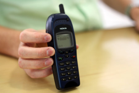 Mobile phone in a woman's hand on a wooden table. Close-up.の写真素材
