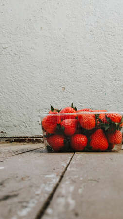 Fresh ripe red organic berry strawberries in a plastic box. Closeup view on a natural texture background. Healthy food conceptの写真素材