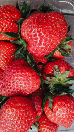 Fresh ripe red organic berry strawberries in a plastic box. Closeup view on a natural texture background. Healthy food conceptの写真素材
