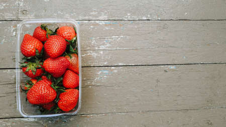 Fresh ripe red organic berry strawberries in a plastic box. Closeup view on a natural texture background. Healthy food conceptの写真素材