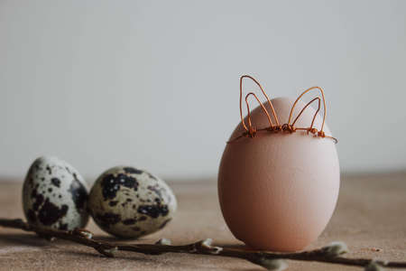 white egg with willow branch and bunny ears on wooden backgroundの写真素材