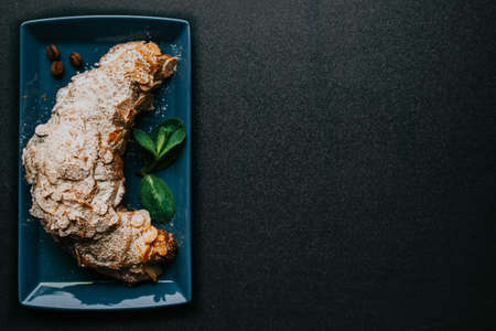 Tasty croissant with powdered sugar and mint on the plate on a dark backgroundの写真素材