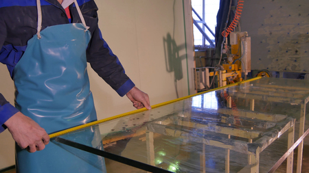 Worker clean and dry the glass on manufacture. Smiling mid adult worker cleaning soap sud on glass window with squeegee. Employee wash the big glass of window on stand. Using water worker clean glass from the dust.の写真素材
