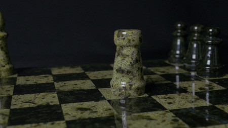 White Rook beats black Elephant on chessboard. Defeated chess Rook. Elephant holding womans hand. Selective focus, close up view. Vintage toning. A rook in chess defeats elephant.の写真素材