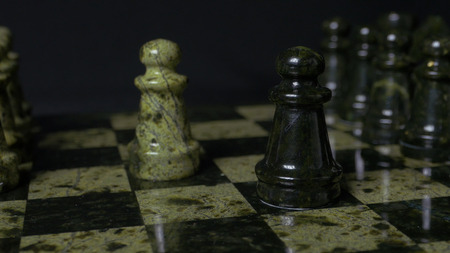 Chess game. White pawn defeats black pawn. Selective focus. Chess pawn defeated pawn. Details of chess piece on black background.の写真素材