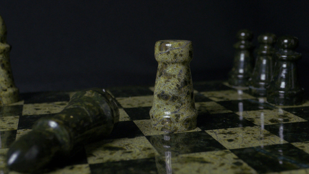 White Rook beats black Elephant on chessboard. Defeated chess Rook. Elephant holding womans hand. Selective focus, close up view. Vintage toning. A rook in chess defeats elephant.の写真素材