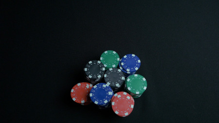 Stack of poker chips and two hands on table. Closeup of poker chips in stacks on green felt card table surface. Poker chips and hands above it on green table. Dealer 4Kの写真素材