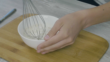 Closeup on mans hands whisking eggs in bowl for cookingの写真素材