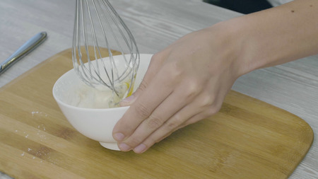 Closeup on mans hands whisking eggs in bowl for cookingの写真素材