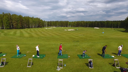 Golfers hitting golf shot with club on course while on summer vacation, aerialの写真素材