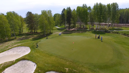 Aerial view of golfers playing on putting green. Professional players on a green golf course.の写真素材