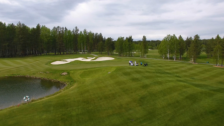 Golfers hitting golf shot with club on course while on summer vacation, aerial.の写真素材