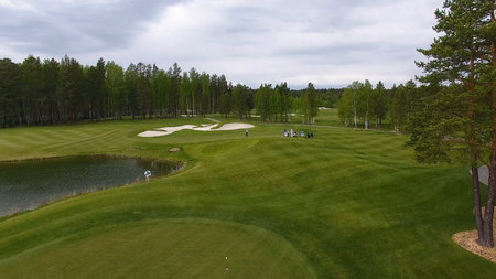 Golfers hitting golf shot with club on course while on summer vacation, aerial.の写真素材