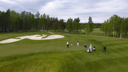 Golfers hitting golf shot with club on course while on summer vacation, aerial.の写真素材