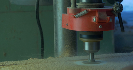 In a furniture factory, a man drills holes for furniture hinges. Drill Forstner. Forstner bit drilling into soft wood, closeup.の写真素材